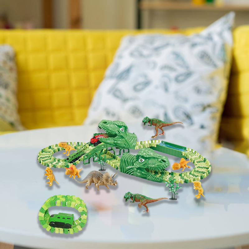 Žalias dinozaurų žaislas su takeliu ant balto stalo, geltona sofa fone.