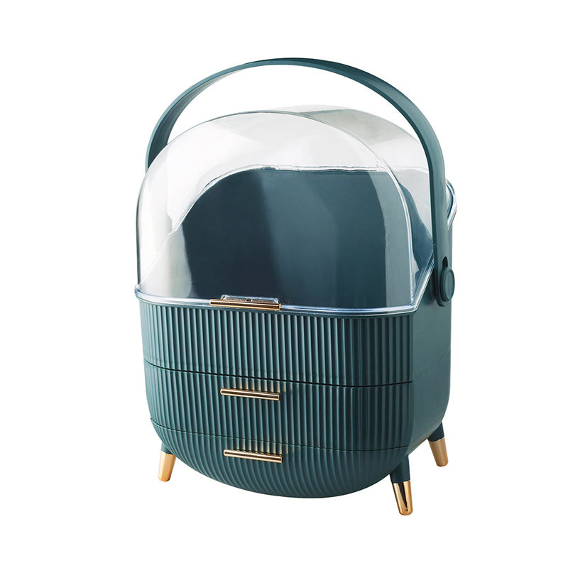 Žalias, apvalus indas su skaidriu dangčiu ir dviem auksinėmis rankenėlėmis.