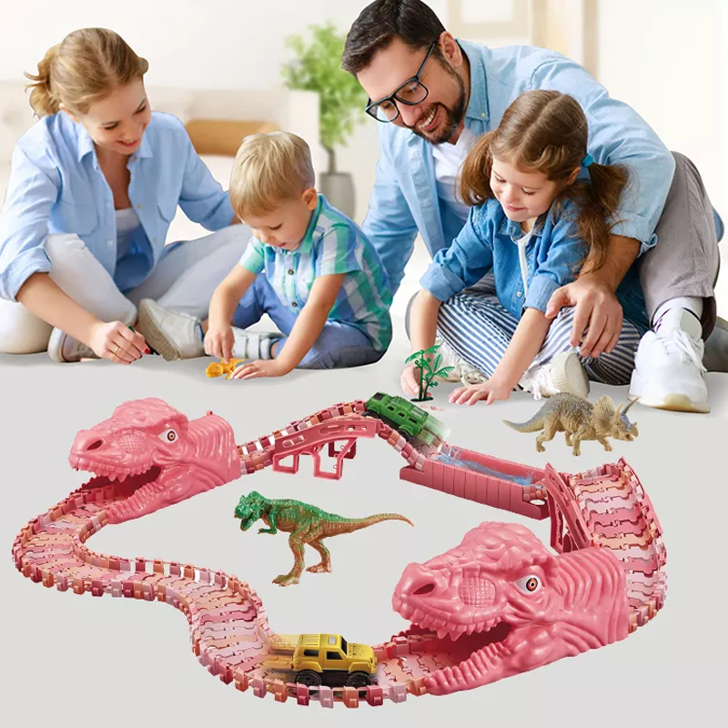 Žaislinis rožinis dinozaurų trasos rinkinys su vaikais ir tėvais, žaidžiančiais aplink.