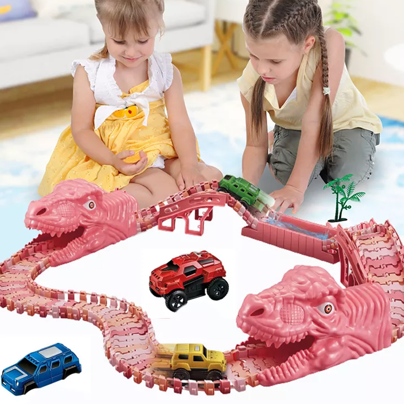 Dvi mergaitės žaidžia su rožiniu dinozaurų formos žaisliniu trasa ir automobiliais.
