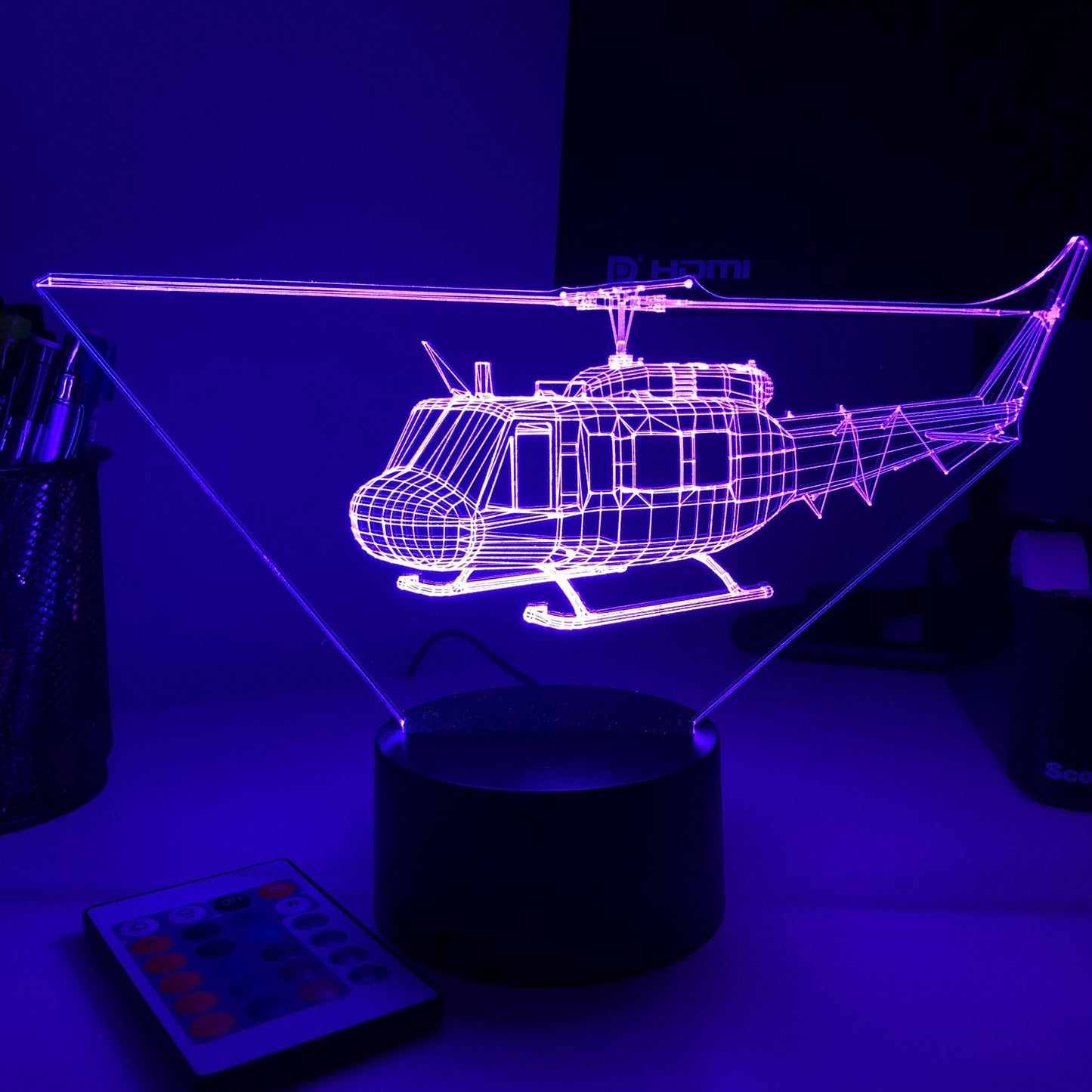 Neoninė violetinė sraigtasparnio forma ant juodo pagrindo, šviečianti tamsiame fone.