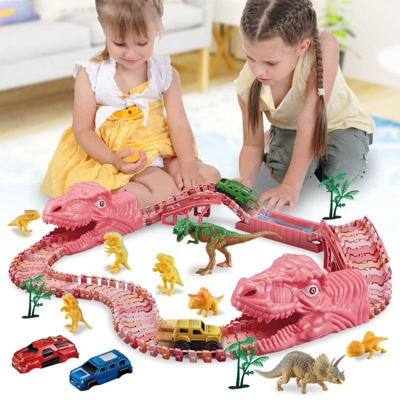 Vaikai žaidžia su rožiniu dinozaurų formos žaislų trasa ir mažais automobiliais.