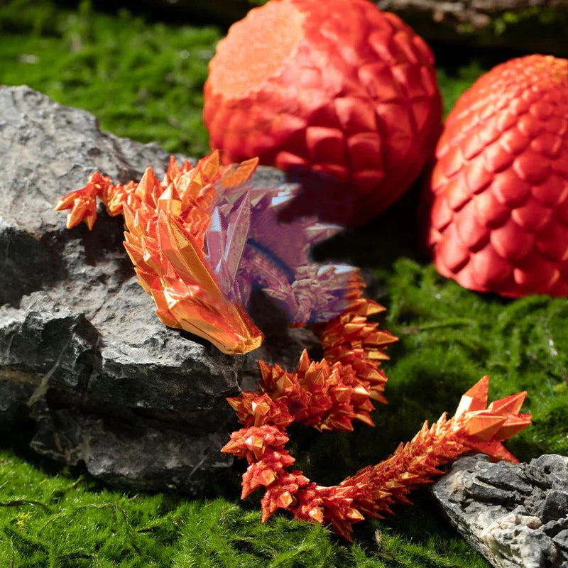 Oranžinis ir raudonas origami drakonas ant akmens, šalia raudoni tekstūruoti rutuliai.