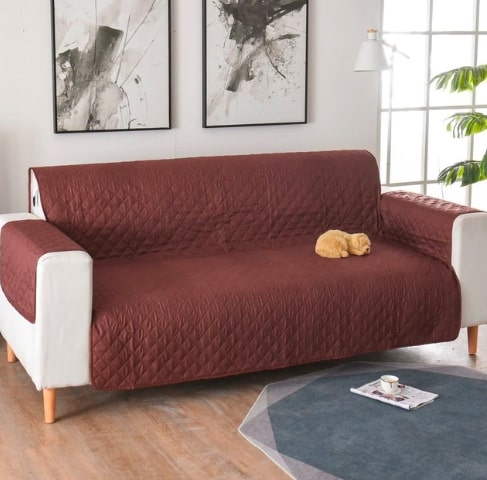 Rudas, siuvinėtas sofa užvalkalas ant baltos sofos, švelni tekstūra.