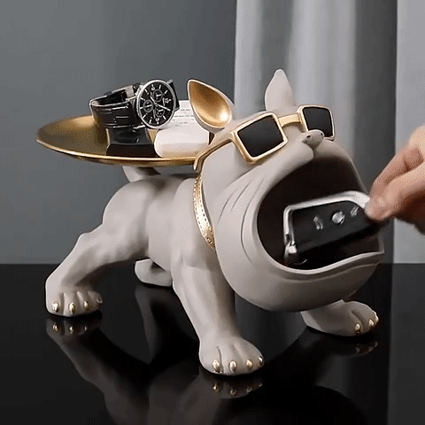 Bulldogo formos laikiklis, pilkas, auksinės detalės, tekstūruotas paviršius, laiko laikrodžius ir telefoną.