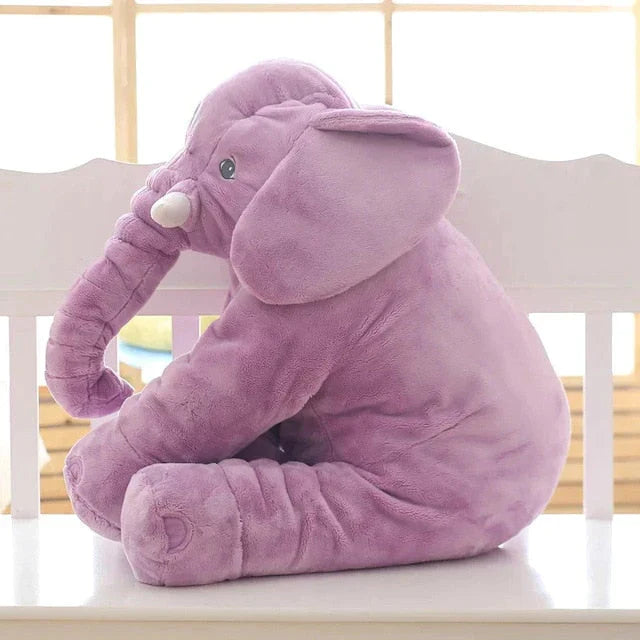 Purios, violetinės spalvos dramblio formos žaislas, sėdintis ant kėdės.