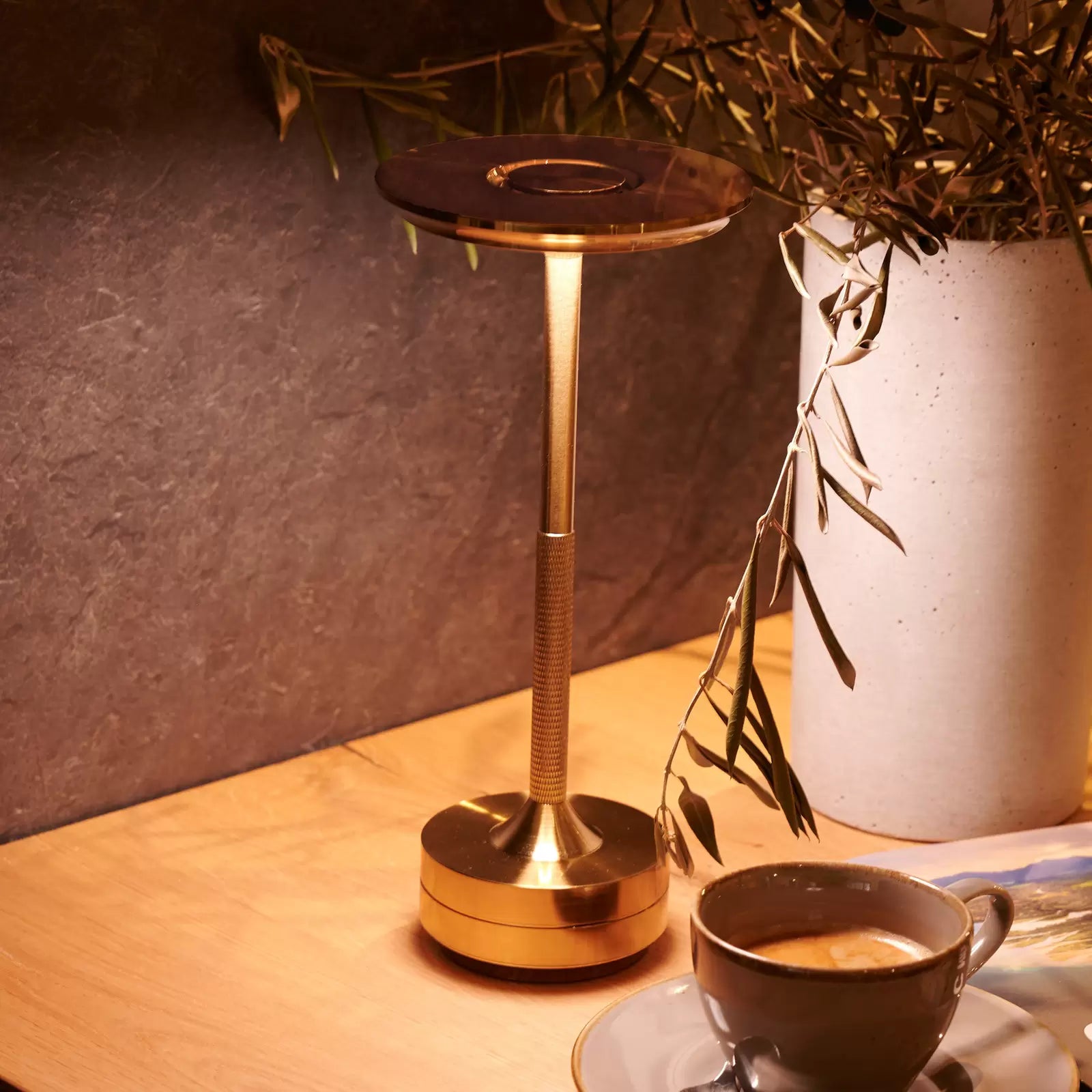 Aukšta, auksinė stalinė lempa su apvaliu, skaidriu gaubtu.