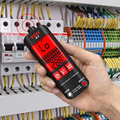 Multimetras laikomas prie elektros skydelio su spalvotais laidais.