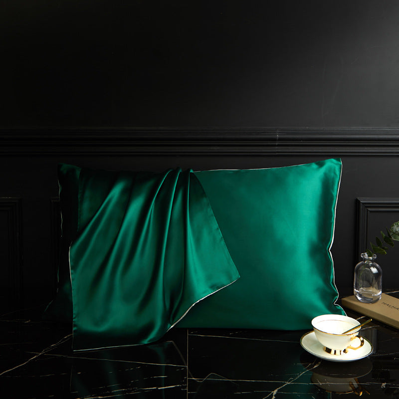 Žalias satino pagalvės užvalkalas su blizgia tekstūra ir elegantišku kraštu.