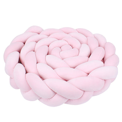 Rožinė, minkšta, pintinė pagalvė, suformuota spiralės pavidalu.