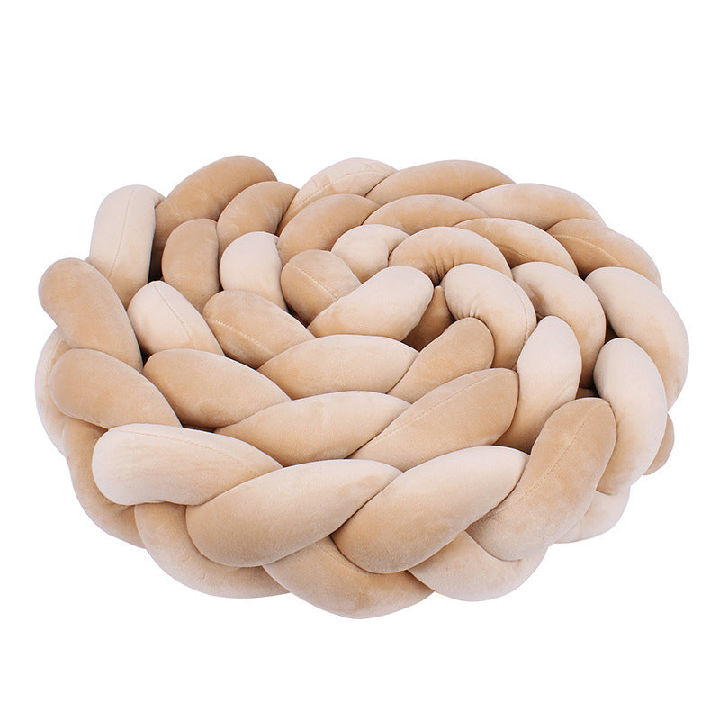 Švelni, smėlio spalvos, pintinė pagalvė su apvalia forma.