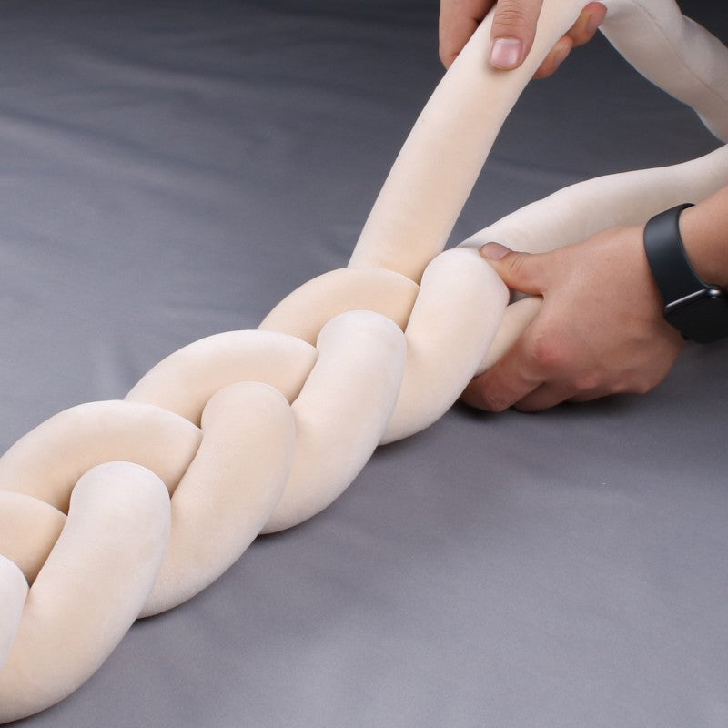 Šviesiai kreminės spalvos, minkštos tekstūros pintinė medžiaga, laikoma rankoje.