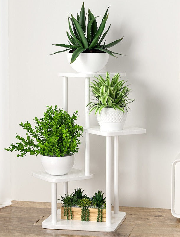 Balta gėlių lentyna su žaliais augalais, skirtingų formų ir dydžių.