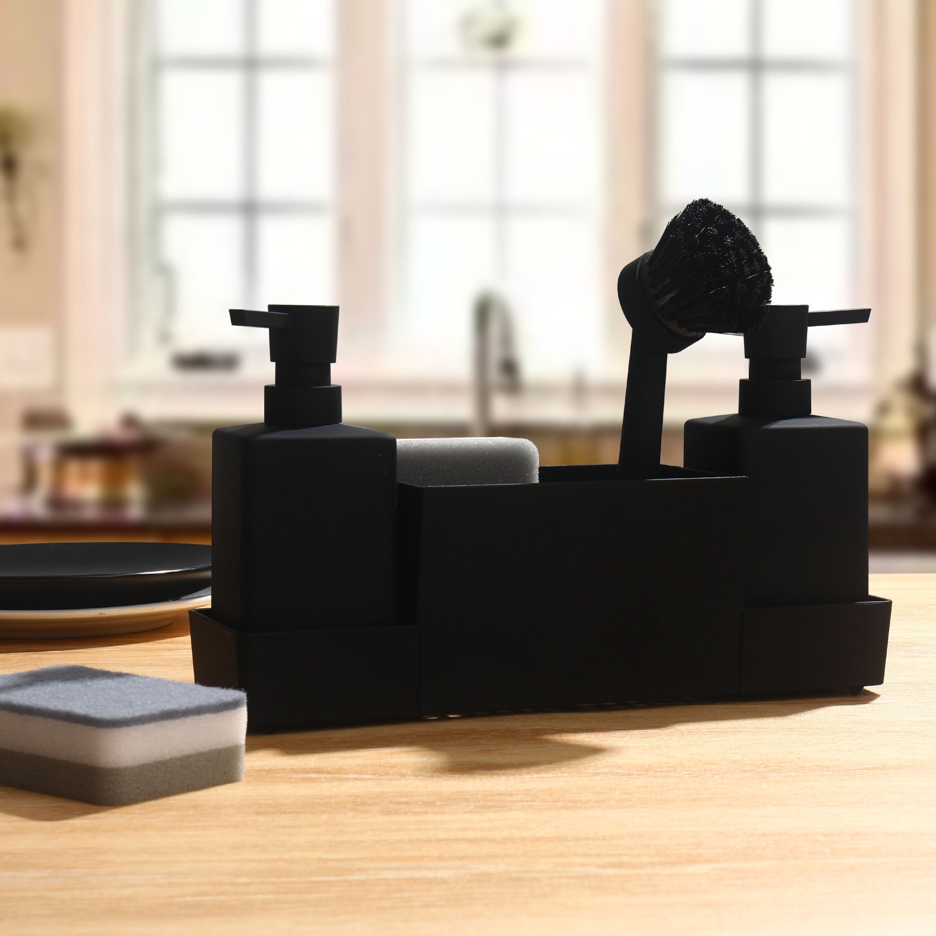 Juodas indas su dozatoriais ir šepetėliu, švelniomis kempinėmis šalia.