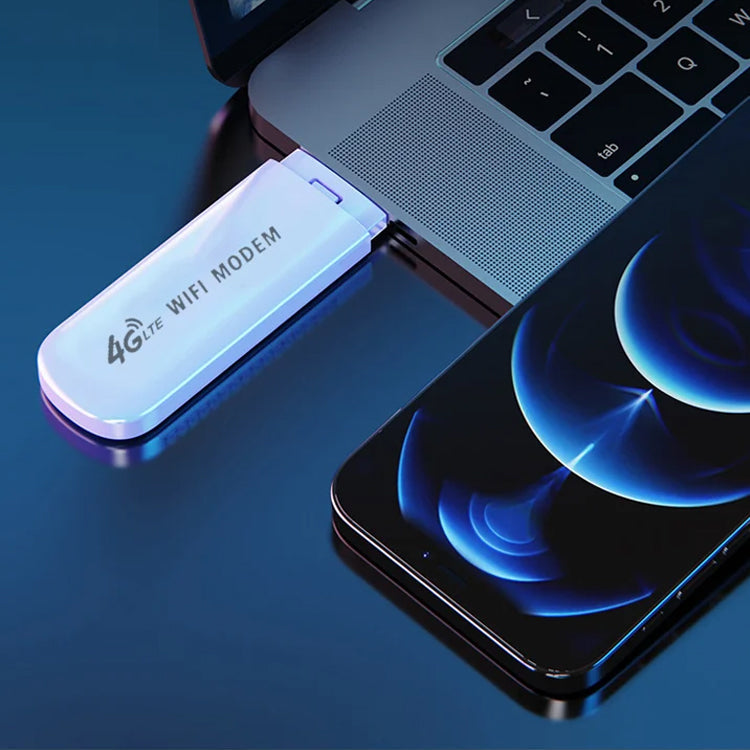 Balta USB modemas prijungtas prie nešiojamojo kompiuterio, šalia juodas išmanusis telefonas.