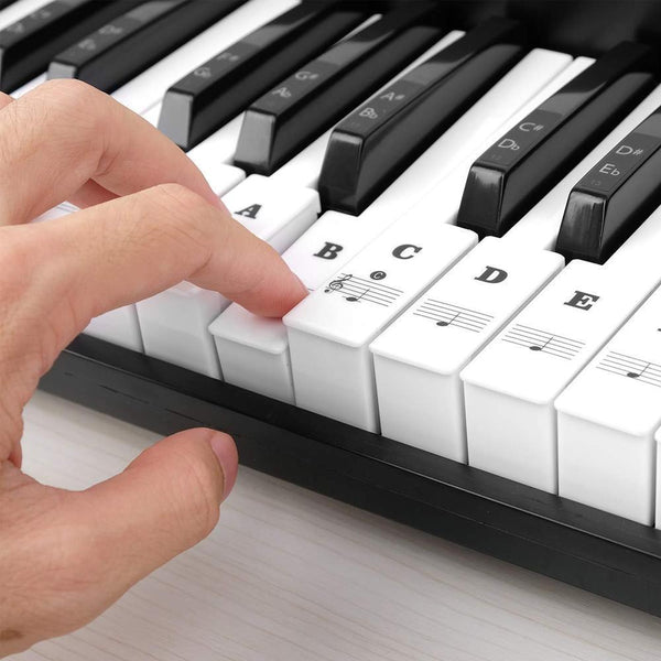 Balti natų lipdukai klijuojami ant pianino klavišų