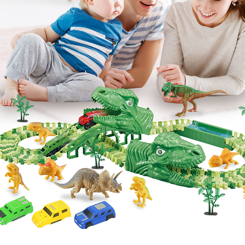 Žaislų trasa su žaliais dinozaurais, automobiliais ir medžiais, vaikai žaidžia.