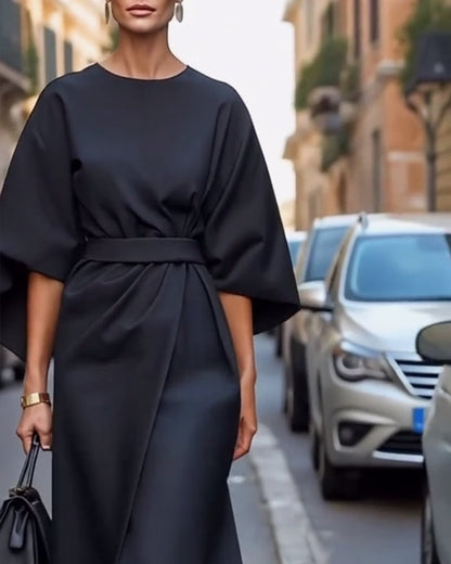 Moteris vilki tamsią elegantišką suknelę su diržu
