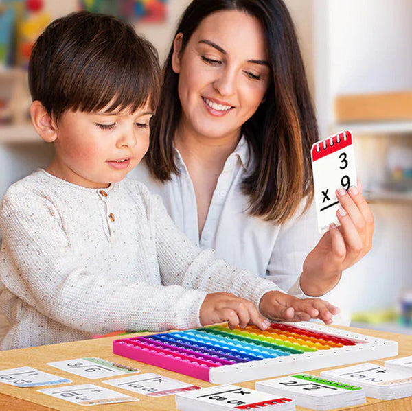Mama ir vaikas prie stalo skaičiuoja naudodami spalvotą matematinį žaidimą.