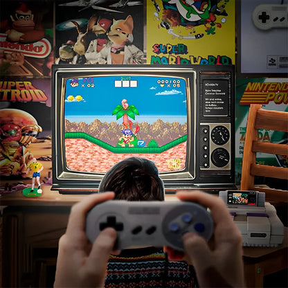 Retro žaidimas televizoriaus ekrane ir pultas žaidėjo rankose