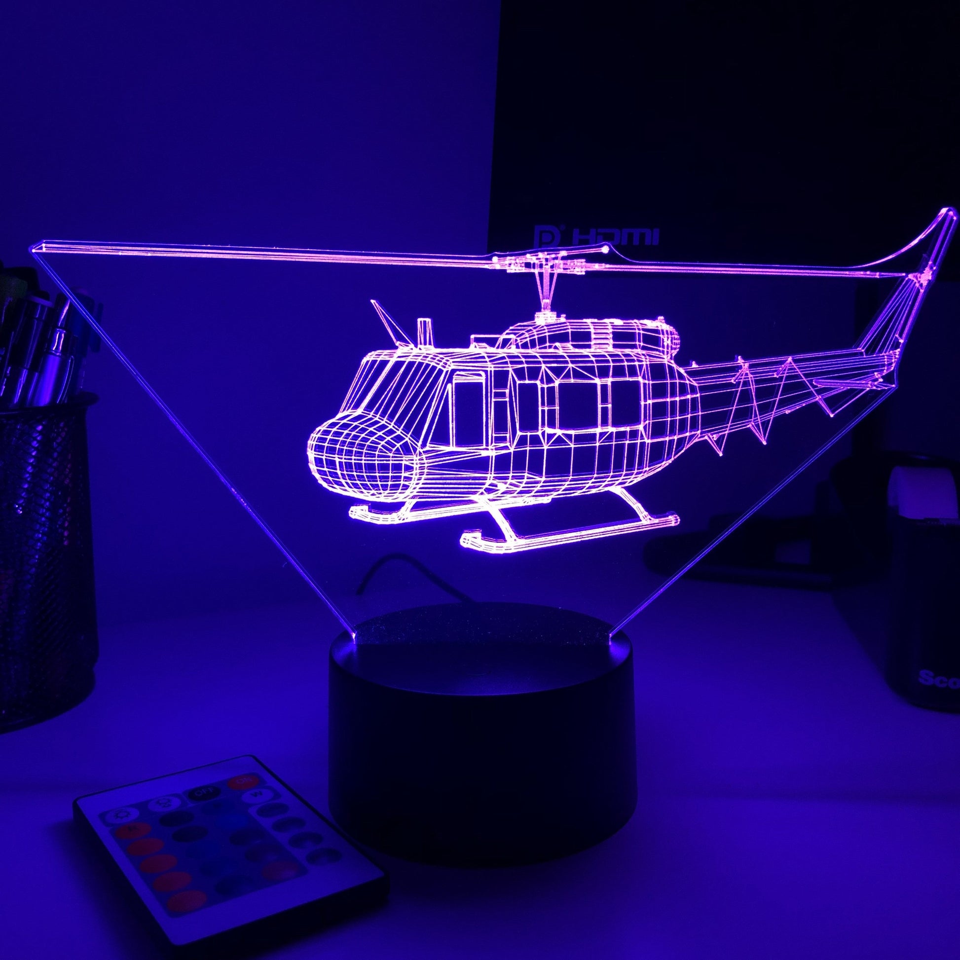 Neoninė violetinė sraigtasparnio forma ant juodo pagrindo, šviečianti tamsiame fone.