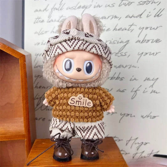 Labubu lėlė: apvali galva, kremiška oda, rudi pūkuoti drabužiai, blizgūs batai