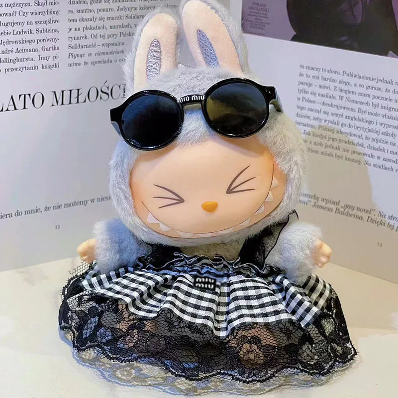 Apvalios formos pilka pūkuota Labubu lėlė su juodais akiniais, languotu nėriniuotu sijonu