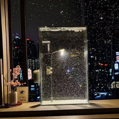 Stačiakampis stiklas su sniego tekstūra, naktinis miestas fone.