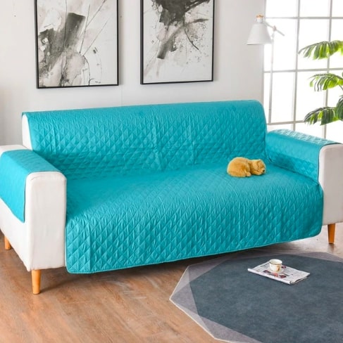 Mėlynas, siuvinėtas sofa užvalkalas ant baltos sofos, švelni tekstūra.