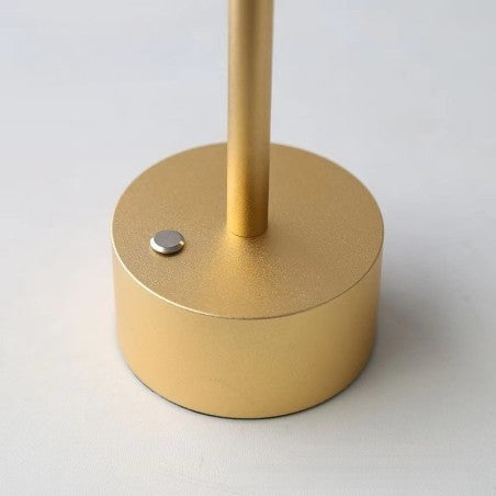 Aukso spalvos apvalus stovas su metaliniu mygtuku, matinė tekstūra.