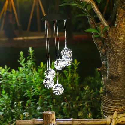 Saulės vėjo varpeliai su LED rutuliais – žali ir balti rutuliai prie medžio