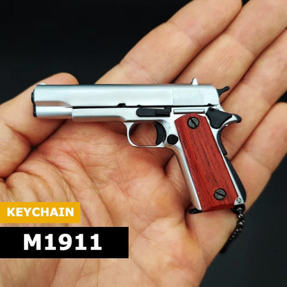 Sidabrinis M1911 pakabukas ruda rankena laikomas delne.
